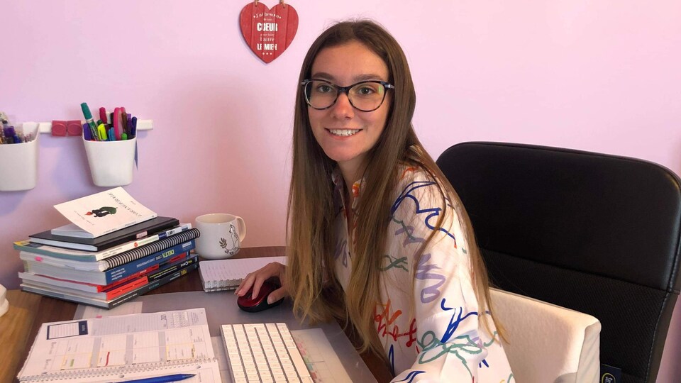 Zoé Ouellet, souriante, assise à un bureau.