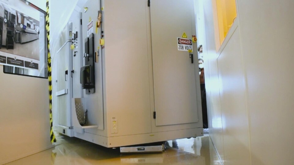 Le robot soulève une grosse charge encombrante tout en tournant le coin d'un corridor étroit.