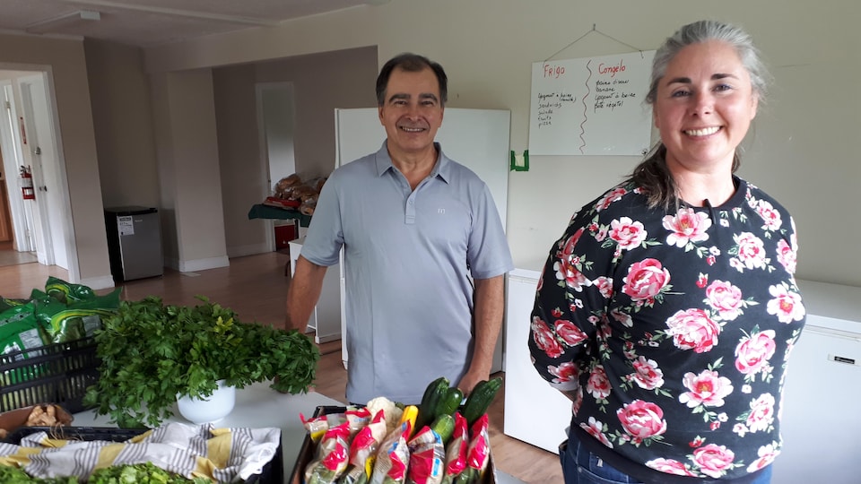 Deux citoyens se tiennent devant des légumes à donner.