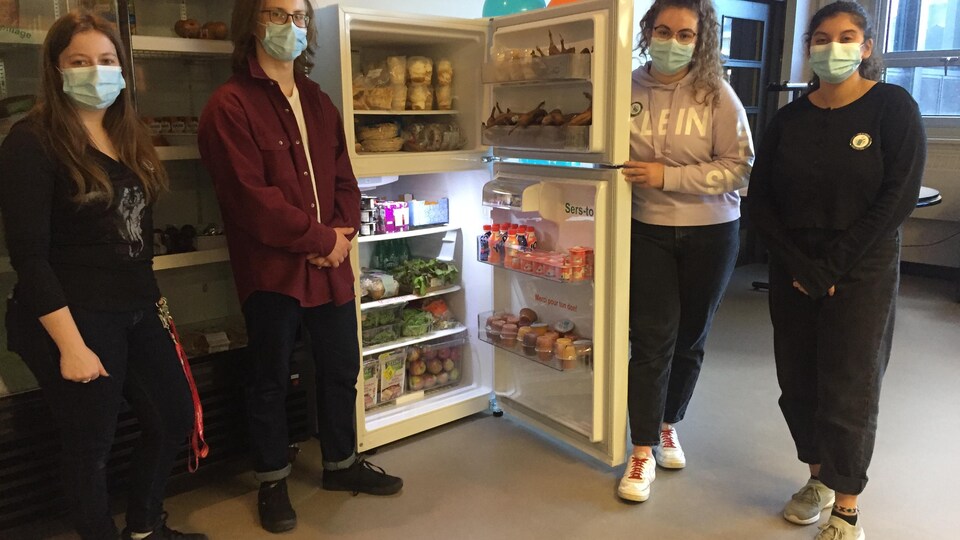 Quatre étudiants à côté d'un frigo rempli.
