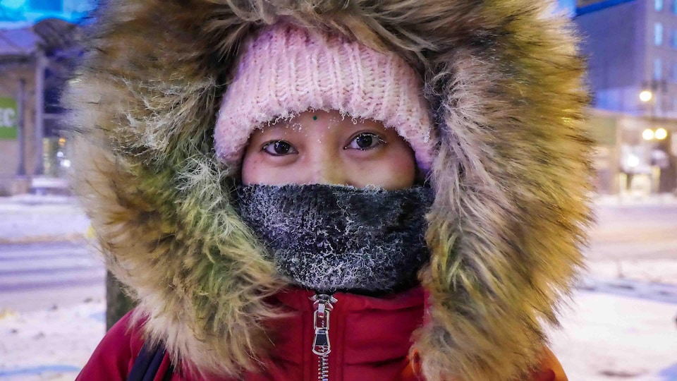 Une femme se couvre le visage pour lutter contre le froid.