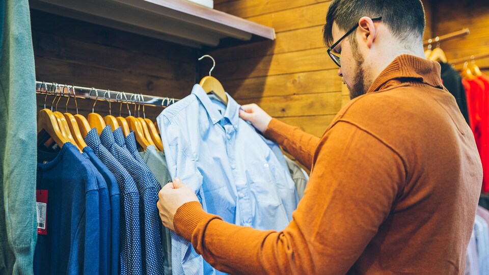 Un homme qui regarde une chemise dans une garde-robe.