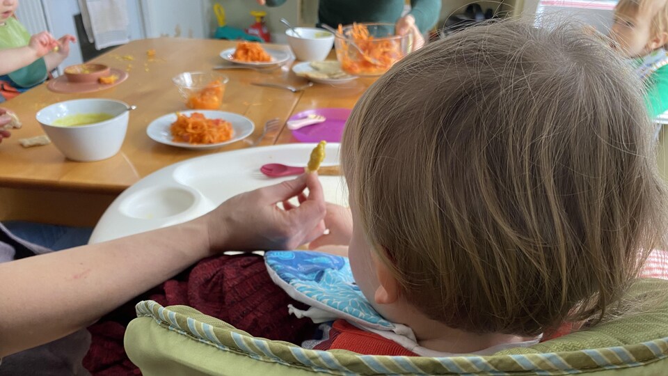 A baby at dinner time, sitting at the table. 