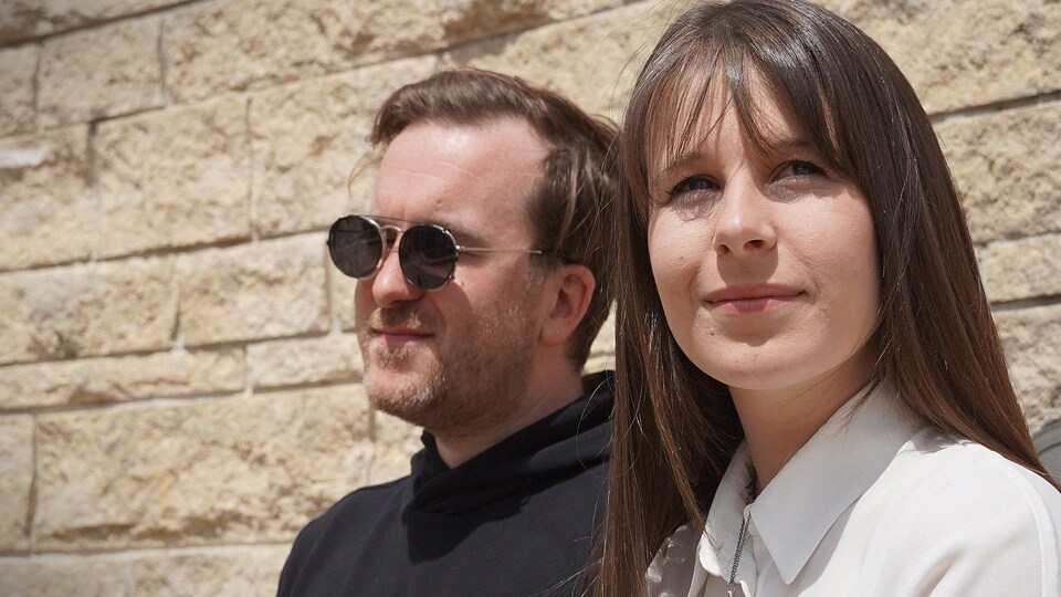 Le duo Geneviève et Alain devant un mur de briques.