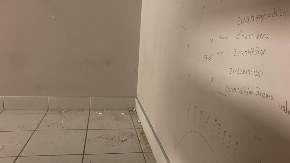 Des mégots de cigarettes sur le plancher et des graffitis sur les murs.