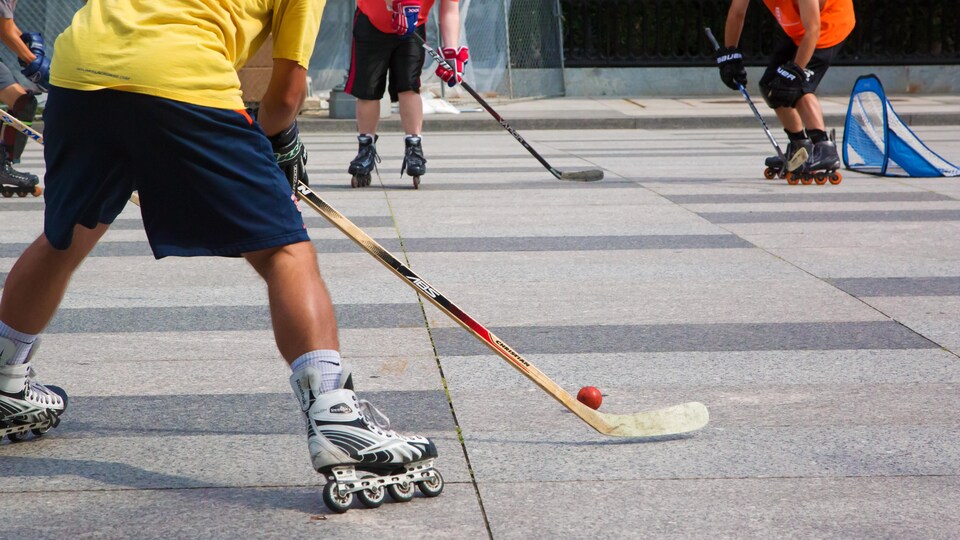Des hommes qui jouent au hockey en patins à roues alignées.