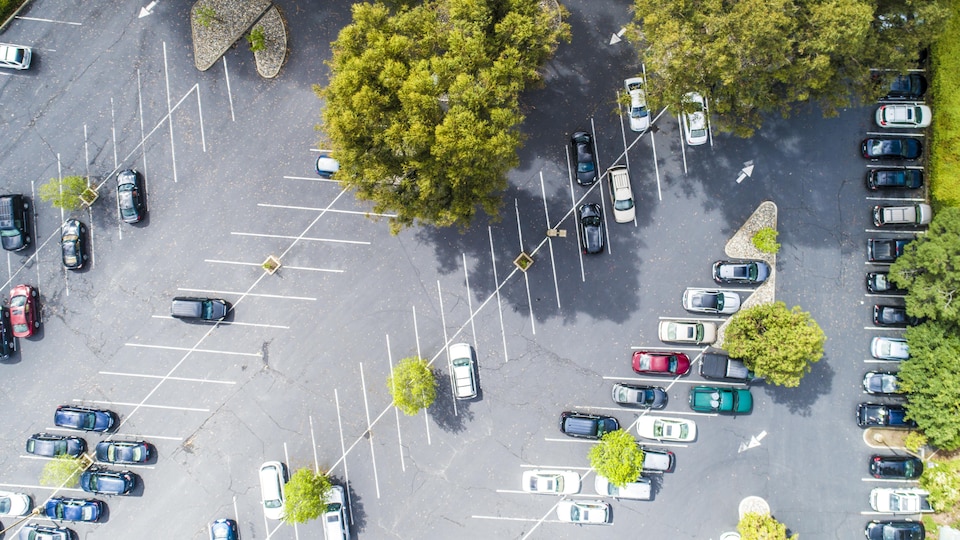 Une vue aérienne d'un grand stationnement avec plusieurs voitures.