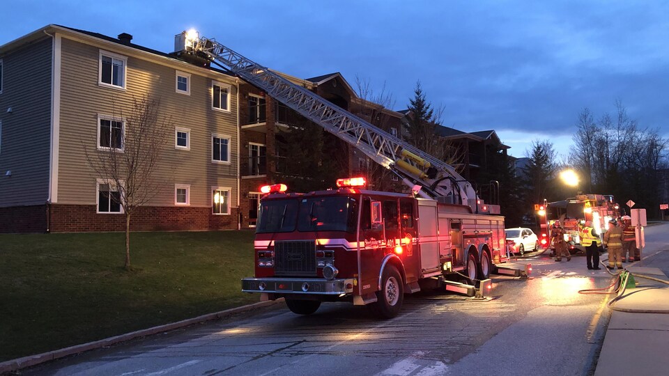 Un camion de pompiers fait face à l'immeuble où a lieu l'incendie.