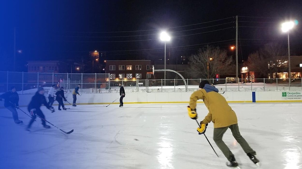 Des jeunes jouent au hockey sur une patinoire extérieure.