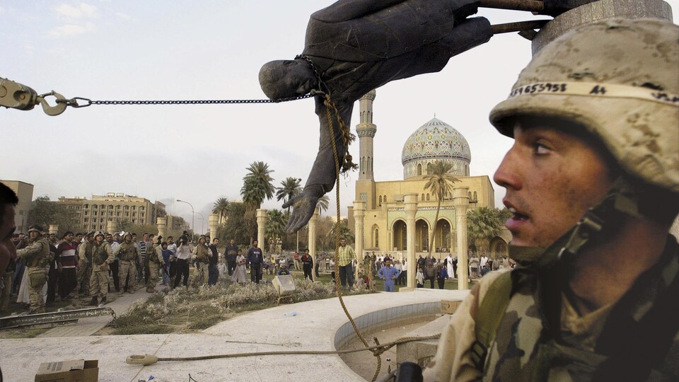 Une statue de Saddam Hussein tombe devant le regard d'un soldat.