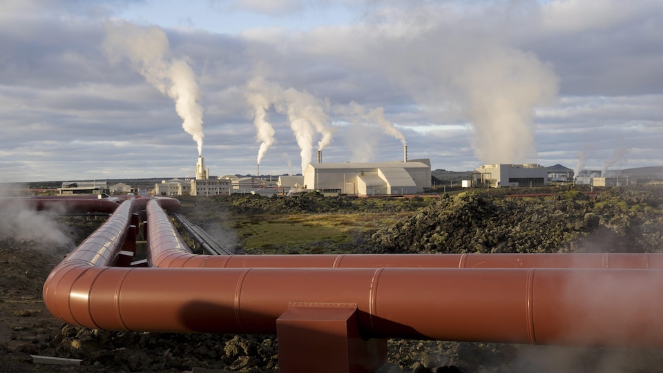 Photo d'une série de canalisations avec en fond l'entreprise d'énergie géothermique HS Orka, en Islande.