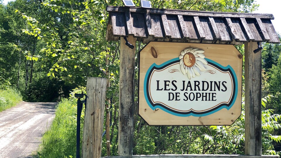 Une pancarte en bois à l'entrée de la ferme sur laquelle on peut lire Les Jardins de Sophie.