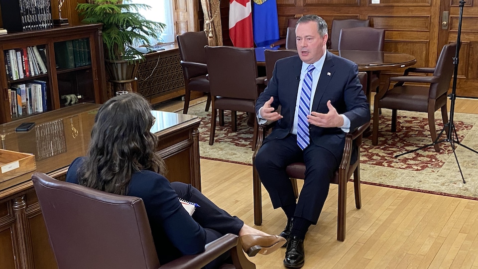Le premier ministre de l'Alberta assis dans son bureau en face d'une journaliste à qui il accorde une entrevue.