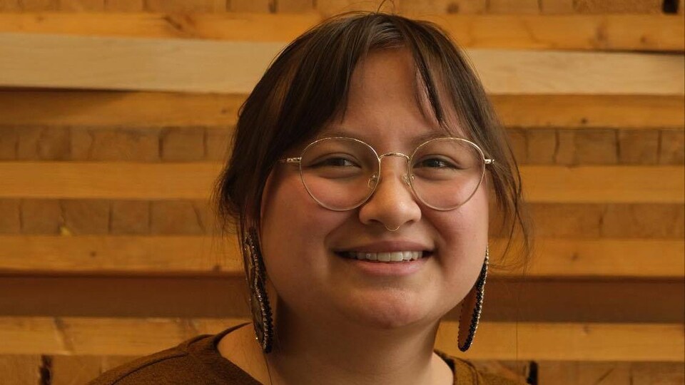 Photo d'une jeune femme portant des lunettes et des boucles d'oreilles traditionnelles.