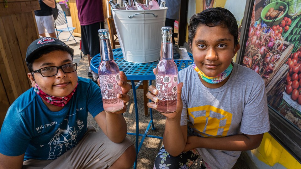 Deux jeunes présentent fièrement leur boisson gazeuse.