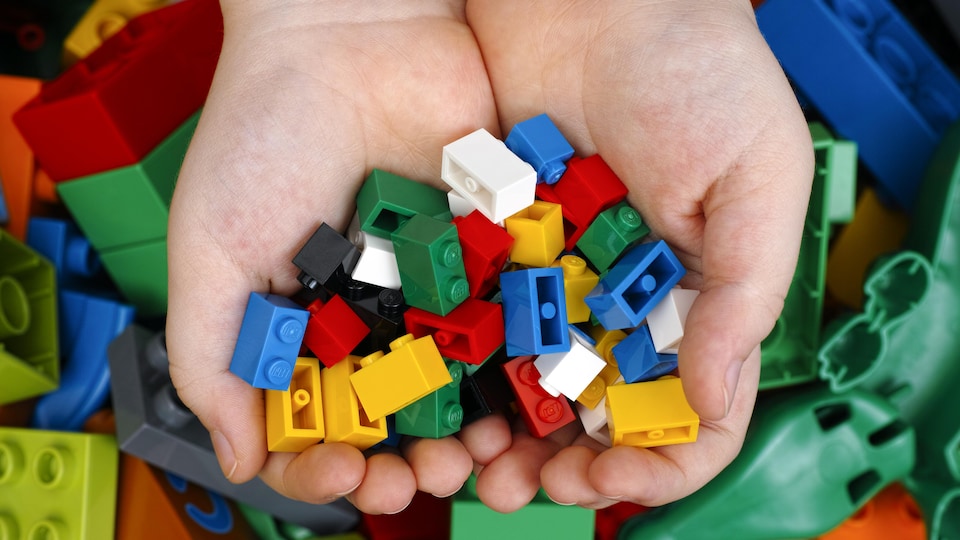 Des mains d'enfants qui tiennent des blocs de construction LEGO.