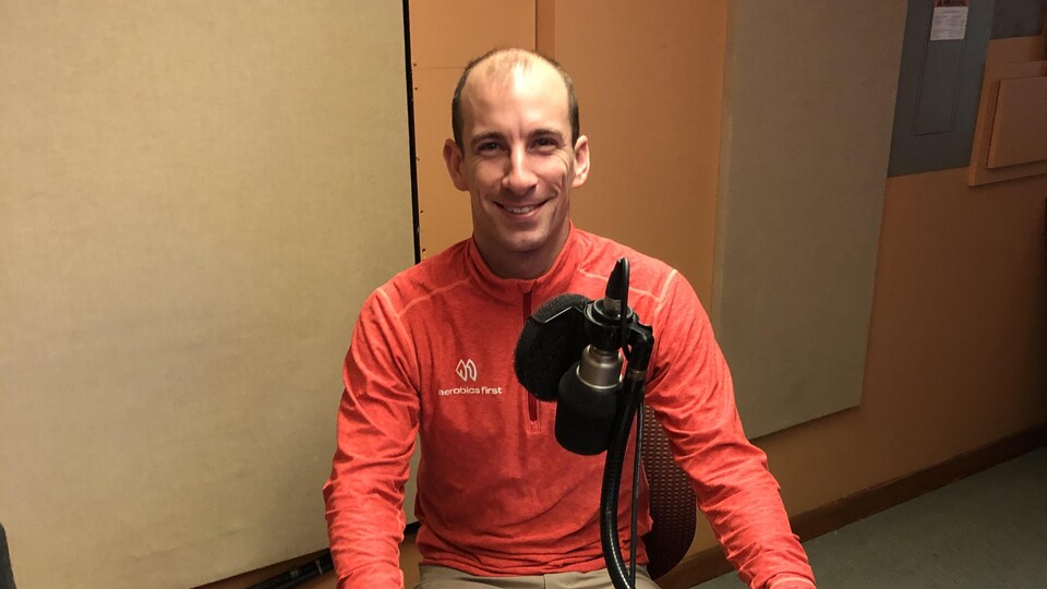 Michaël-Lucien Bergeron, membre de l'armée canadienne et athlète, portant une chemise rouge. Il se trouve dans un studio radio et est devant un microphone.