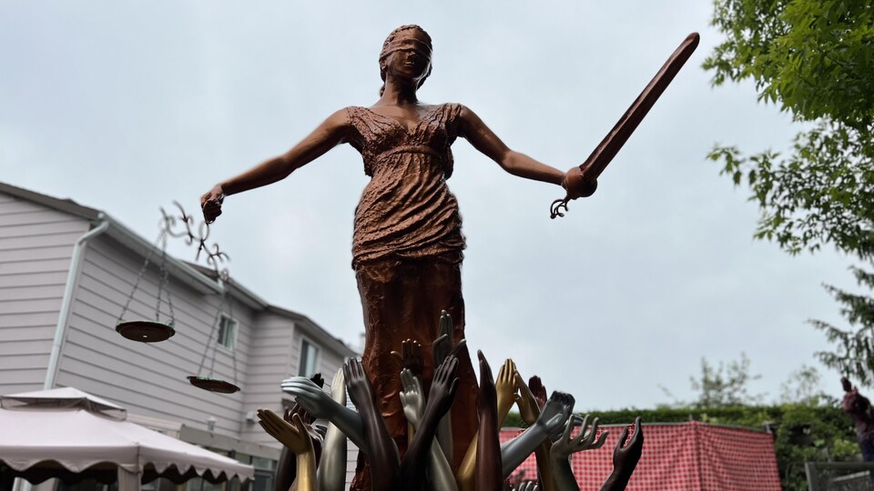 Une grande sculpture d'une femme avec un bandeau sur les yeux et qui tient une balance et une épée.