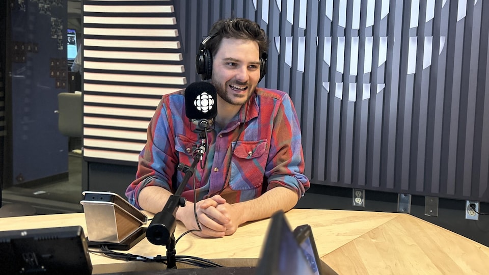 Julien Morissette est assis devant un micro dans un studio de radio.
