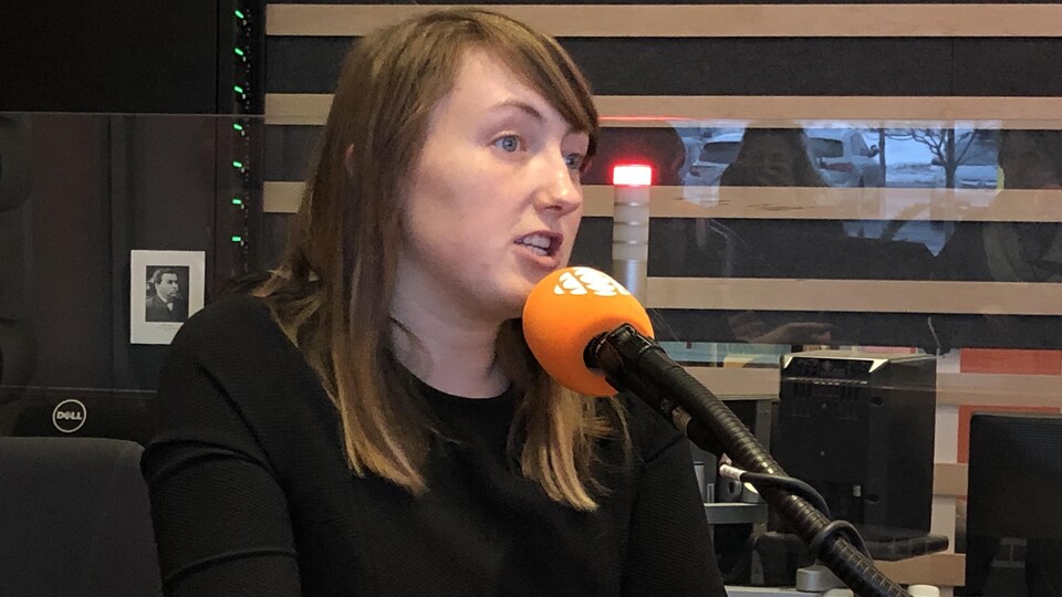Une femme est en studio et parle devant un micro.