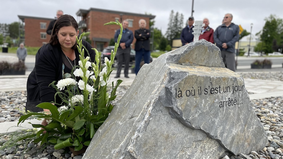 La mairesse de Lac-Mégantic, Julie Morin, dépose un caillou devant une roche commémorative de la tragédie.