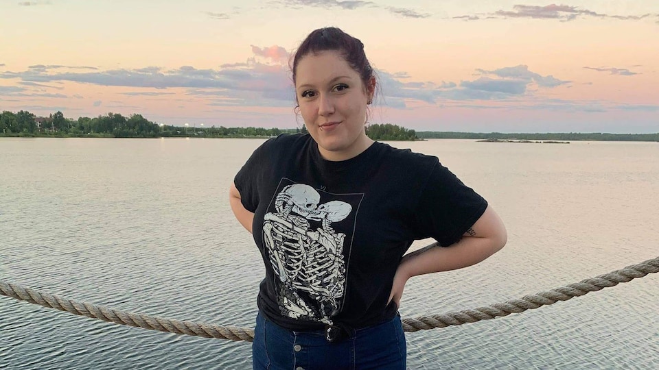 Une jeune femme pose devant un lac.