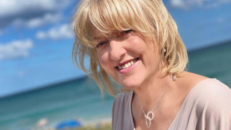 Lina Boudreau sur le bord de la mer, sourit à la caméra.