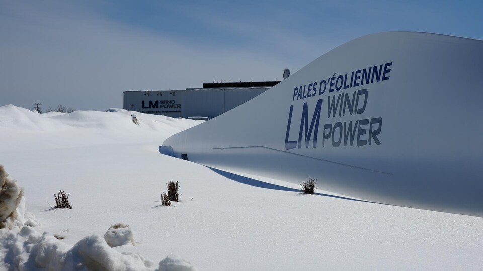 Une pale d'éolienne dans la neige avec le logo de LM Wind Power.
