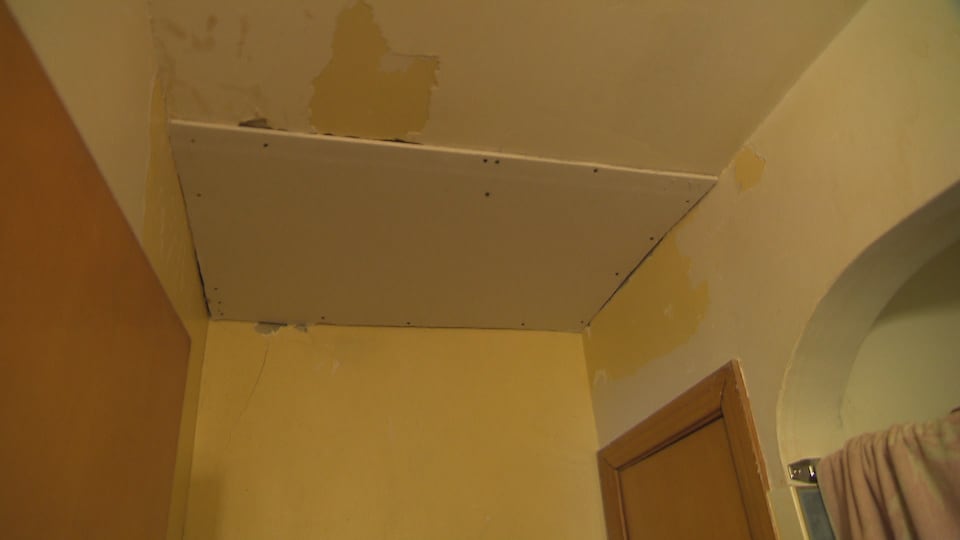 Un plafond d'appartement en mauvais état a été couvert par une planche pour tenter de masquer le dégât. 