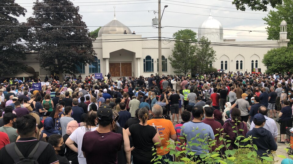 Un grand groupe de personnes rassemblées devant une mosquée.