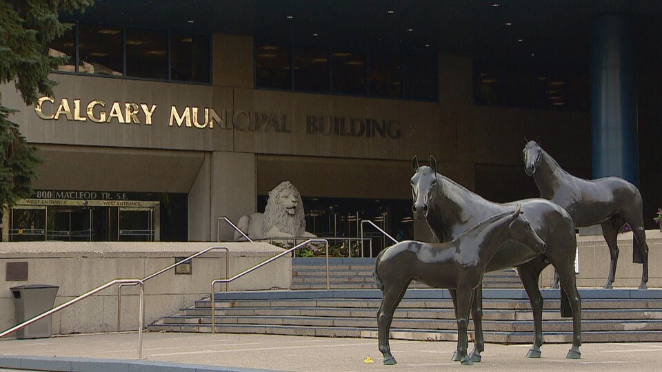 Entrée de l'hôtel de ville de Calgary. Des statues de troix chevaux sont placées sur des marches. Une statue de lion est placée devant les portes d'entrée.