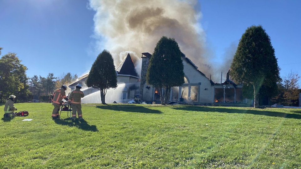 Les pompiers arrosent une maison pour tenter d'éteindre l'incendie.