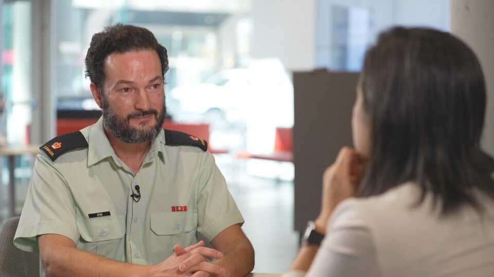 Le major André Jean qui est le coprésident militaire national de l'organisation consultative de la Fierté de l'équipe de la défense, est assis avec la journaliste Marie-Lou St-Onge. 