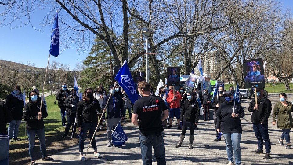 Une vingtaine d'employés sont dehors avec des pancartes.