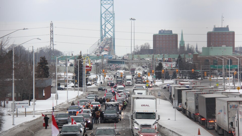 Des véhicules arborant des drapeaux canadiens devant le pont Ambassador, visiblement congestionné.