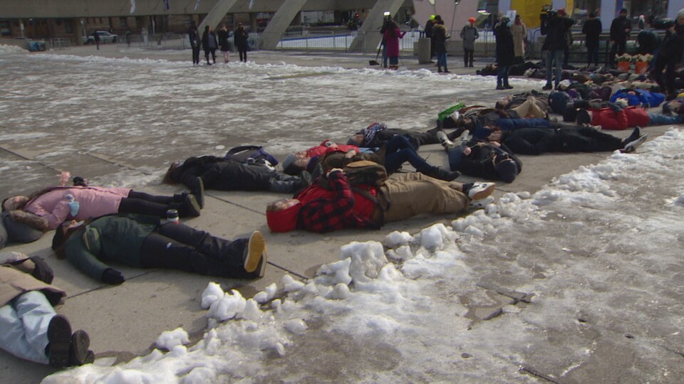 Des personnes allongées au sol devant l'hôtel de ville de Toronto.