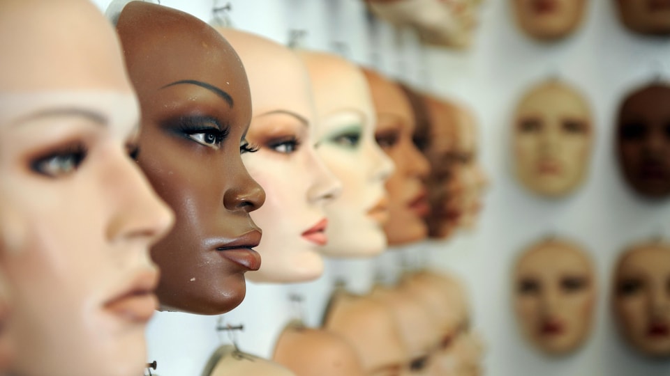 Des têtes de mannequins sur un mur.