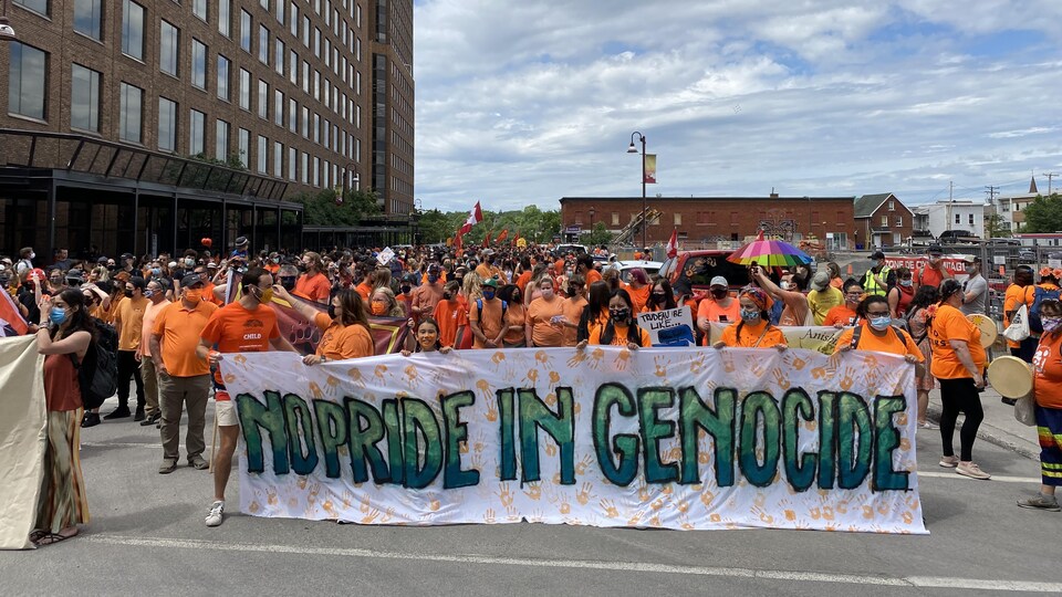 Des participants vêtus d’orange tiennent une banderole.
