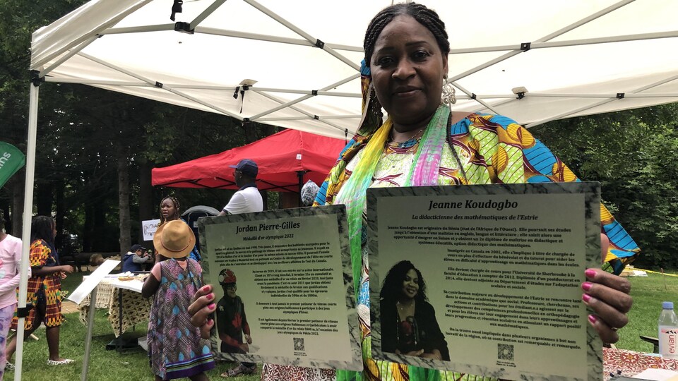 Mariame Cissé tient dans ses mains deux plaques à l'effigie de bâtisseurs issus des communautés noires.