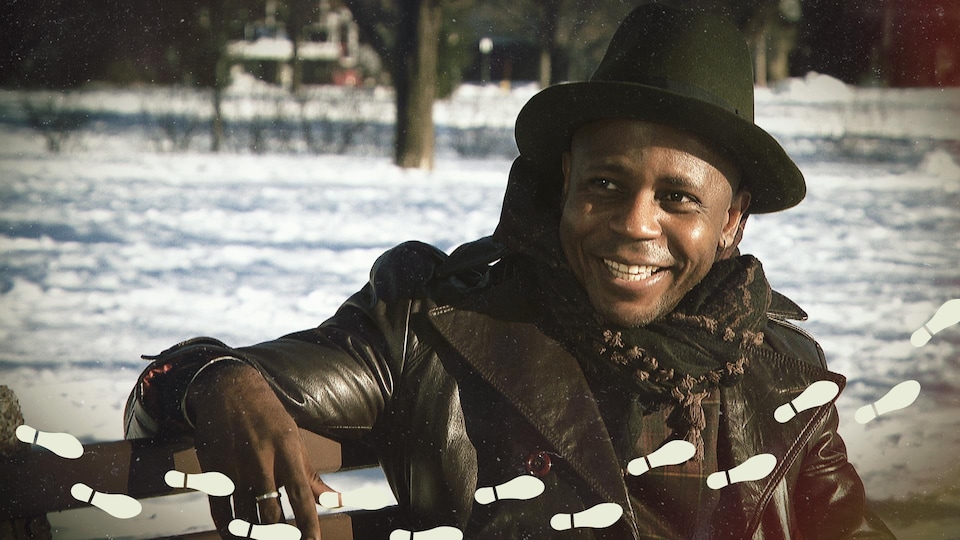 Le R Premier, souriant, assis sur un banc de parc en hiver.