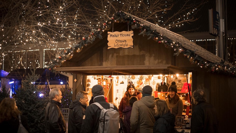 Plusieurs personnes devant un kiosque dans un marché de Noël.