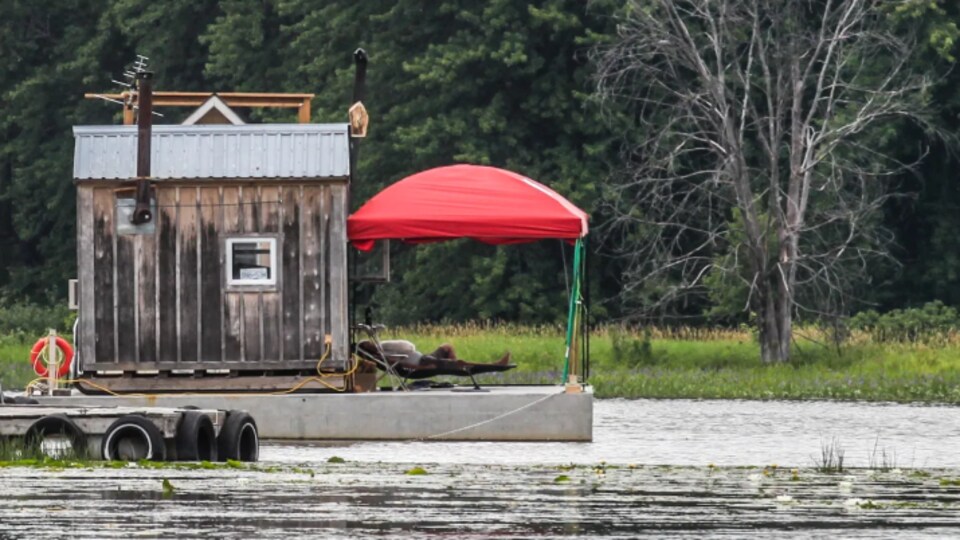Un homme et son chien font une sieste à proximité d’une cabane flottante à la marina près de l’île Pétrie.