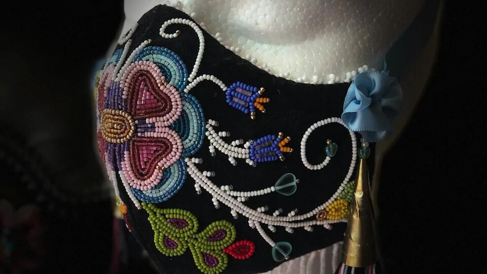 Le masque noir en broderie perlée de l'artiste Lisa Shepherd est composé de fleurs de multiples couleurs.