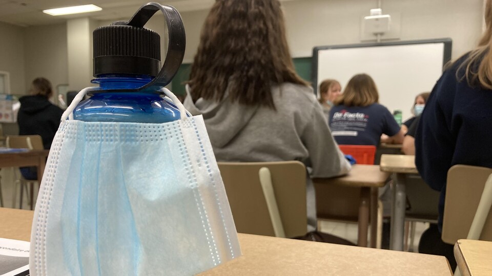 Un masque sur une bouteille d'eau dans une classe. 