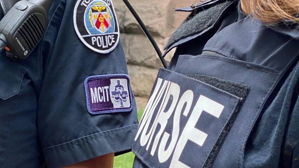 Plan resserré sur deux uniformes de membres d'une équipe mobile d'intervention en cas de crise de la police de Toronto.