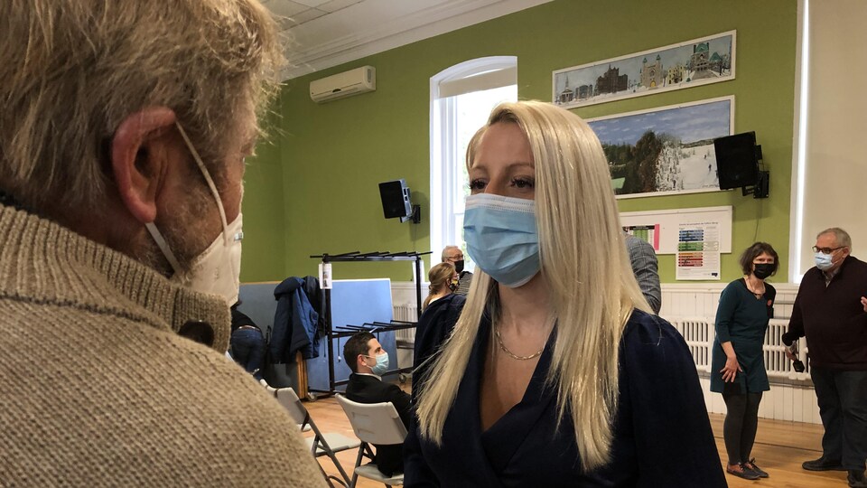 Masque sur le visage, Mélissa Généreux discute avec un homme.