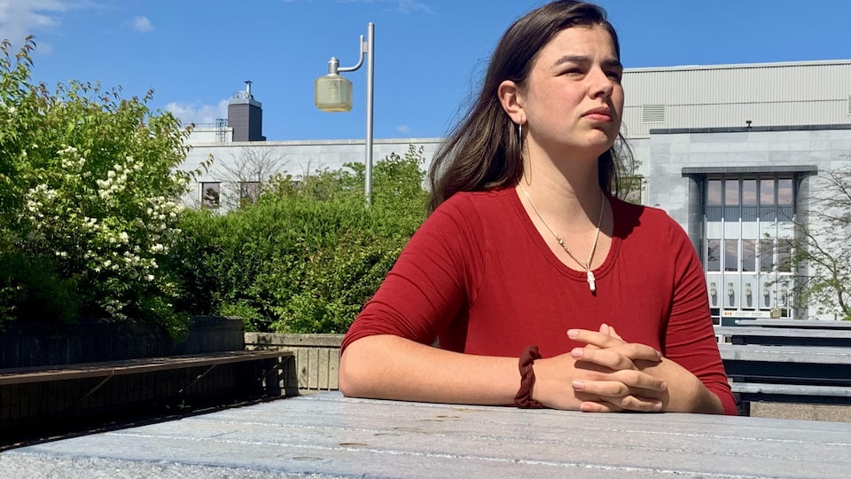 Une jeune fille assise à une table à l'extérieur.