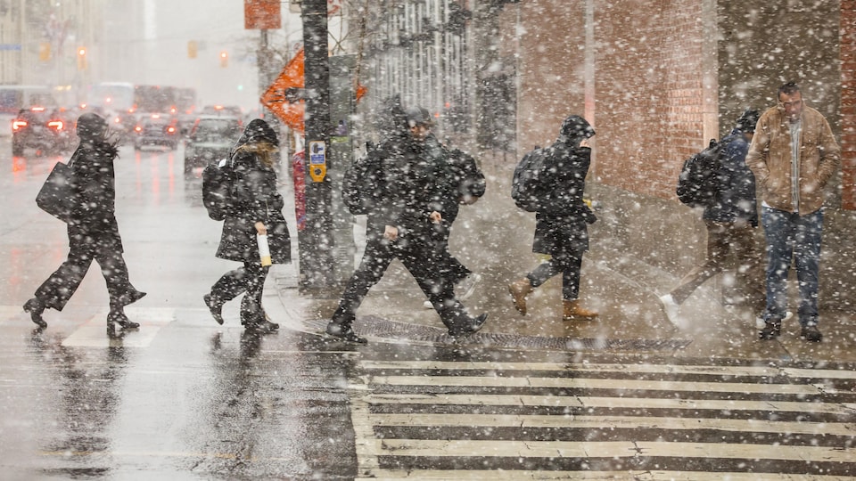 Des personnes marchent sous une chute de neige.