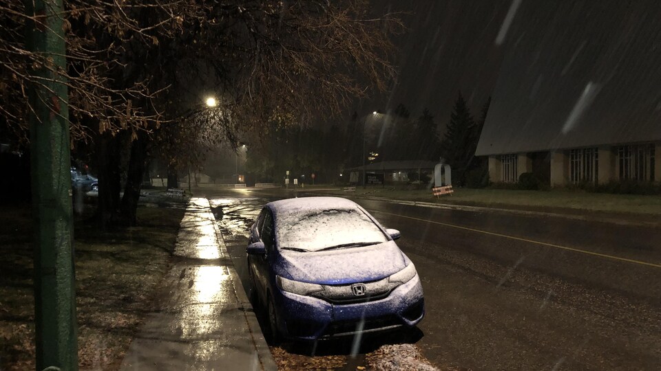 Une voiture couverte de neige alors que Regina subit des précipitations nocturnes.