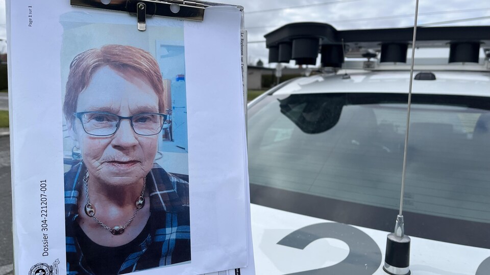 La photo d'une femme âgée à proximité d'un véhicule de police.